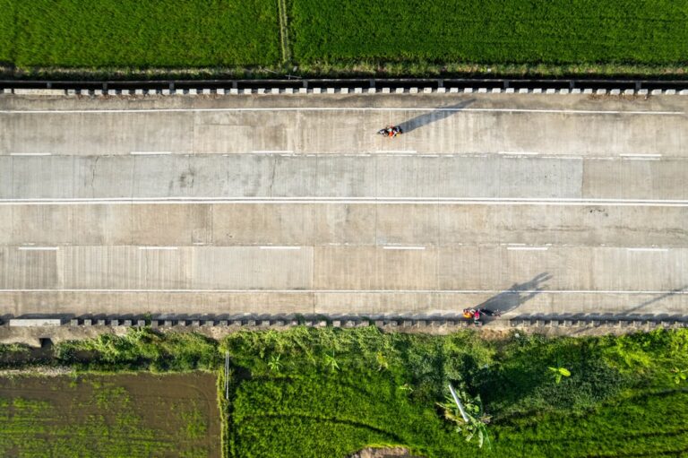 Aerial drone shot of a major new highway interchange under construction on a bright, sunny day, symbolizing large-scale in...
