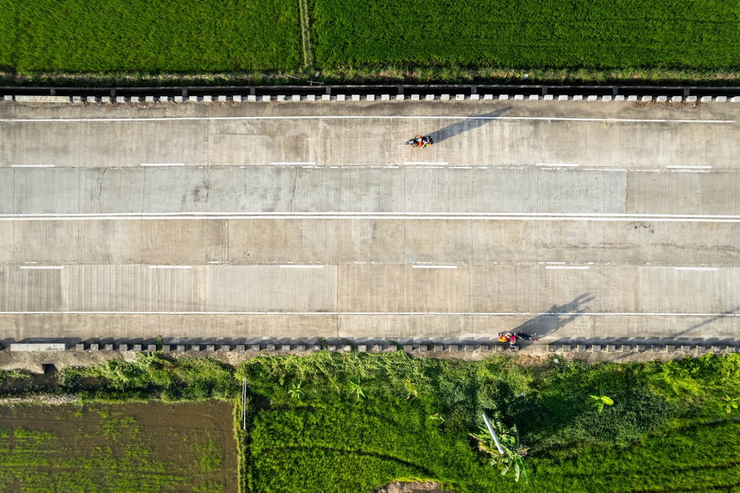 Aerial drone shot of a major new highway interchange under construction on a bright, sunny day, symbolizing large-scale in...