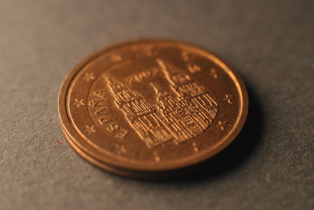 Hand carefully placing a single coin onto a miniature house, symbolizing real estate commission savings.