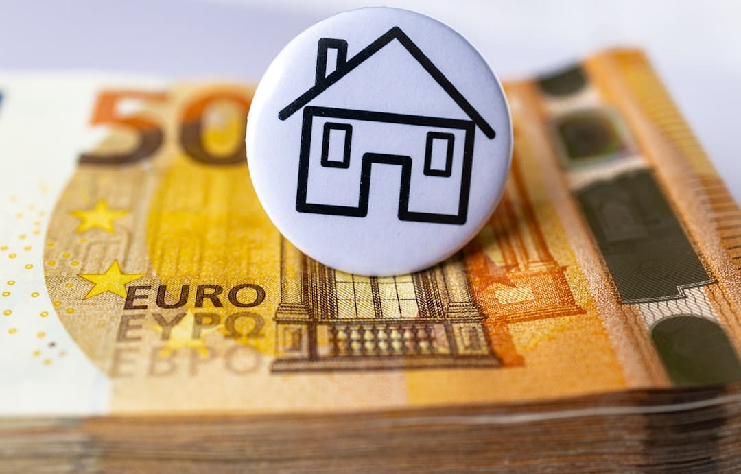 A minimalist top-down view of a modern house key and a small, neat stack of coins on a clean, bright background, representing real estate savings.