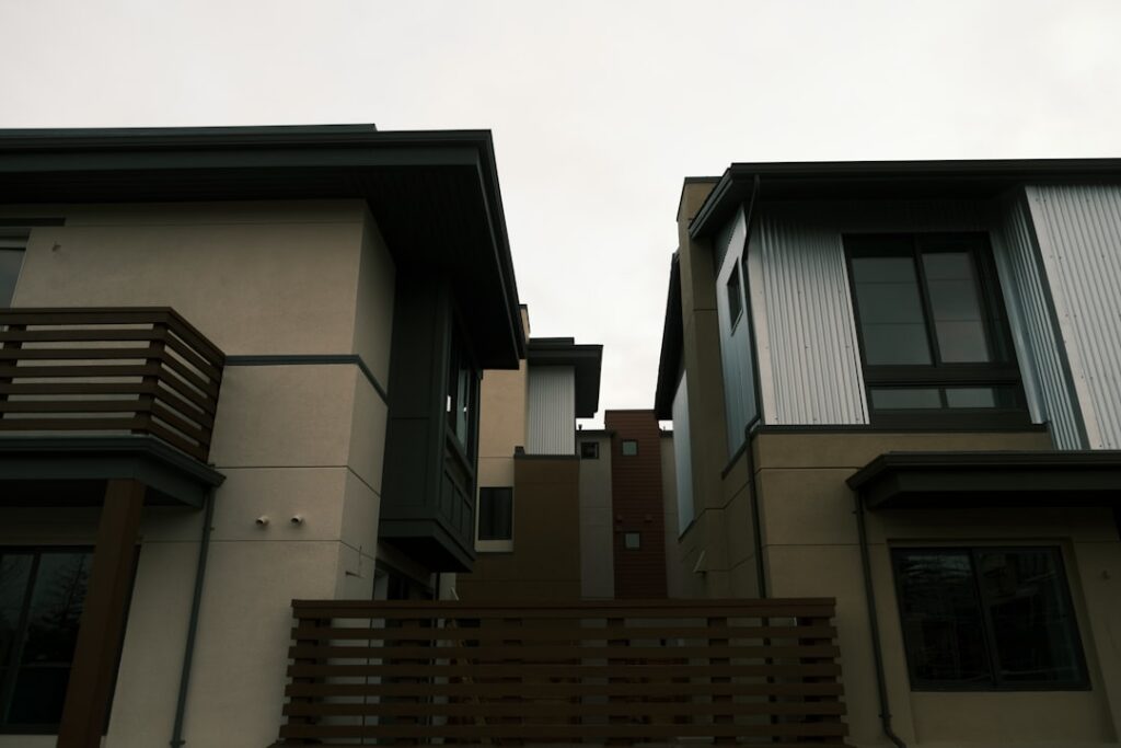 Side-by-side view of two distinct, modern suburban homes under a bright, clear sky, representing a choice in real estate s...