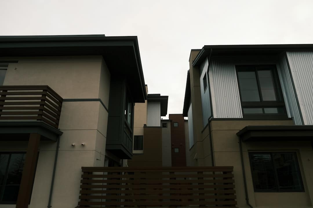 Side-by-side view of two distinct, modern suburban homes under a bright, clear sky, representing a choice in real estate s...