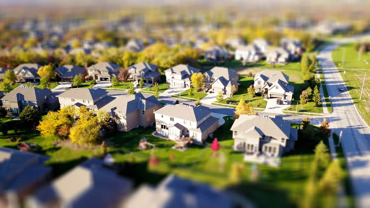 A bright 'Sold' sign in the front yard of an attractive suburban home with a pristine new roof, representing a successful and stress-free sale.