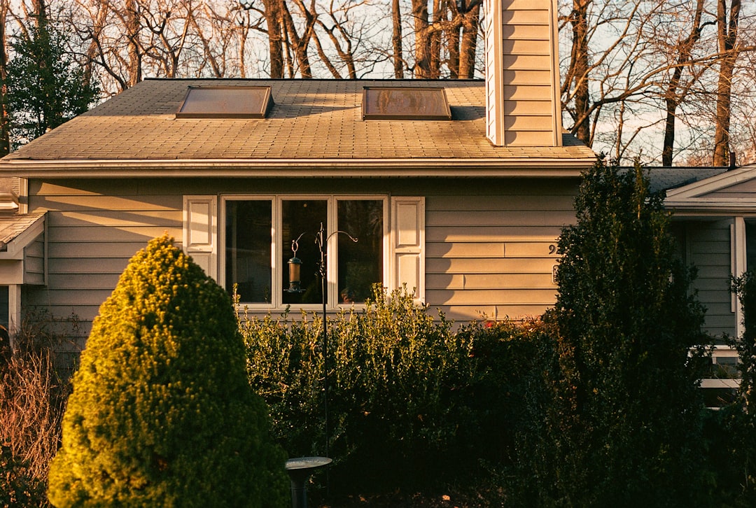 A beautiful, modern suburban home with a brand new roof shining under a clear, sunny sky, representing a secure and insurable property for buyers.