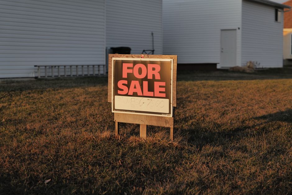 A beautiful, modern suburban house on a sunny day with a 'For Sale' sign in the manicured front lawn, symbolizing the major financial asset at stake when selling a home.