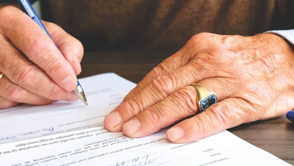 A close-up, professional shot of a person's hands signing a real estate contract on a clean, organized desk, symbolizing the start of the selling process.