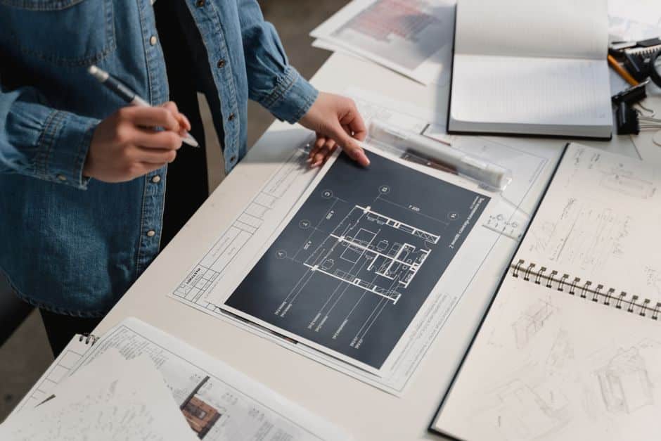 Bright, modern workspace with architectural blueprints of a house spread across a clean desk, symbolizing strategic home s...