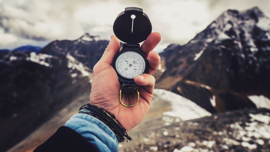 A close-up, professional shot of a hand holding a modern compass, representing the clarity and expert guidance needed to navigate the complex real estate market.