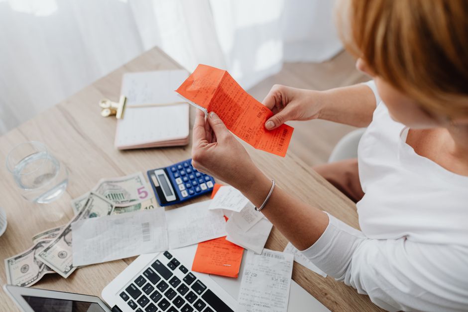 A homeowner sits at a modern kitchen island with a laptop and calculator, carefully planning their finances for a home sale.