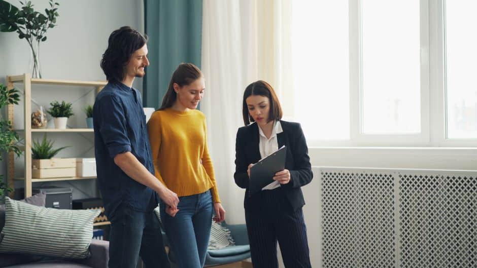 A professional and friendly real estate agent sits with clients at a dining table in a modern home, showcasing a full-service, high-quality consultation.