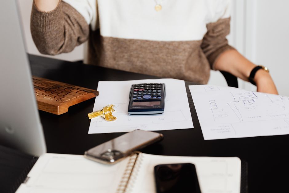 A professional individual at a modern desk reviewing financial documents with a calculator and house keys nearby, illustrating the strategic financial planning involved in selling a home.