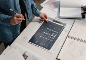 Bright, modern workspace with architectural blueprints of a house spread across a clean desk, symbolizing strategic home s...