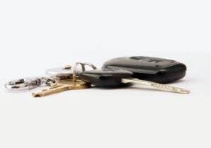 Heavy, rustic boat anchor lies on a wooden surface next to a set of modern house keys, visually representing the financial...